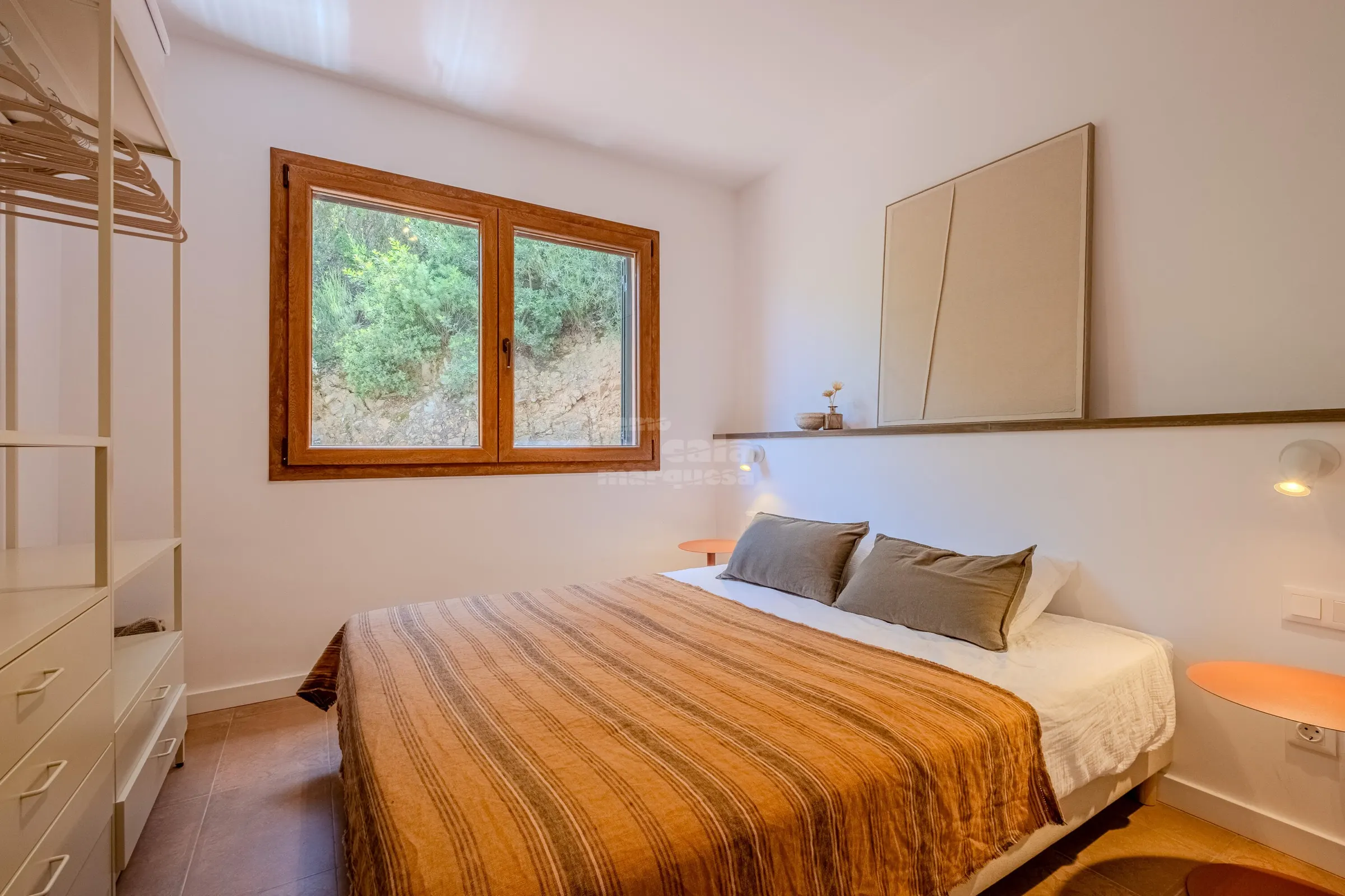 Garden bedroom with striped ochre bedspread and built-in wardrobes