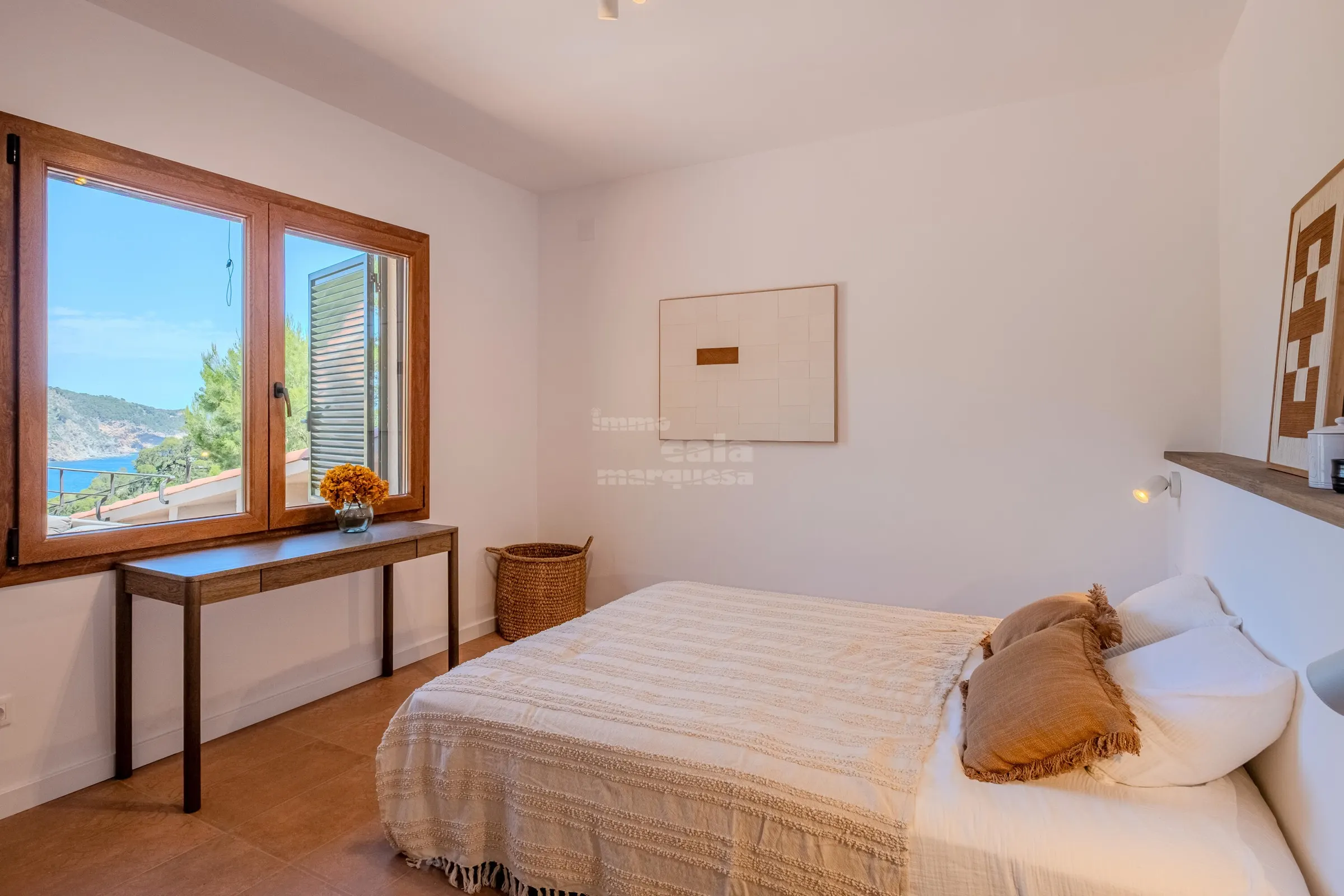 Double bedroom with a picture window over the bay and a console with fresh marigolds
