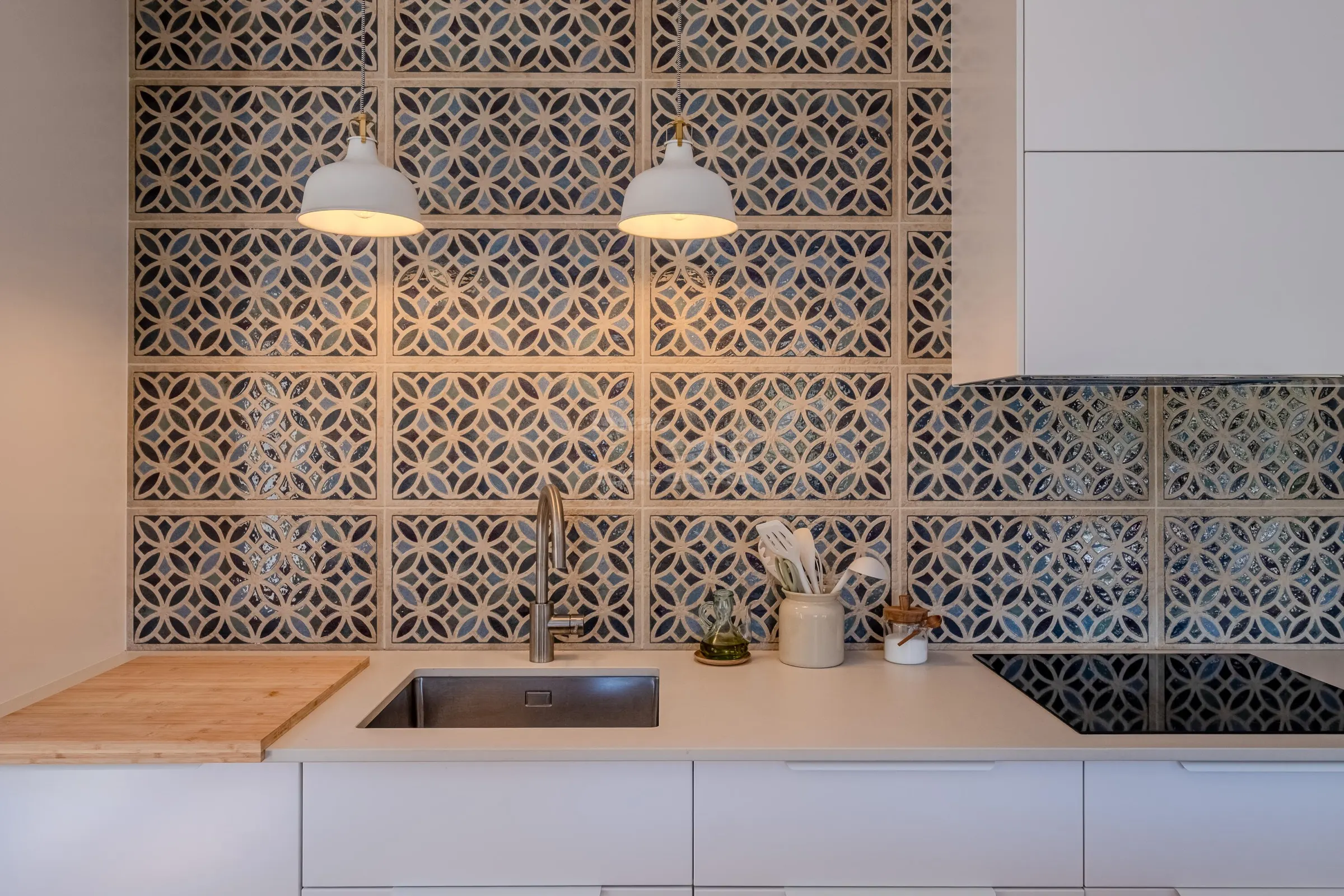 Kitchen with handmade patterned tiles, twin pendant lamps and induction hob