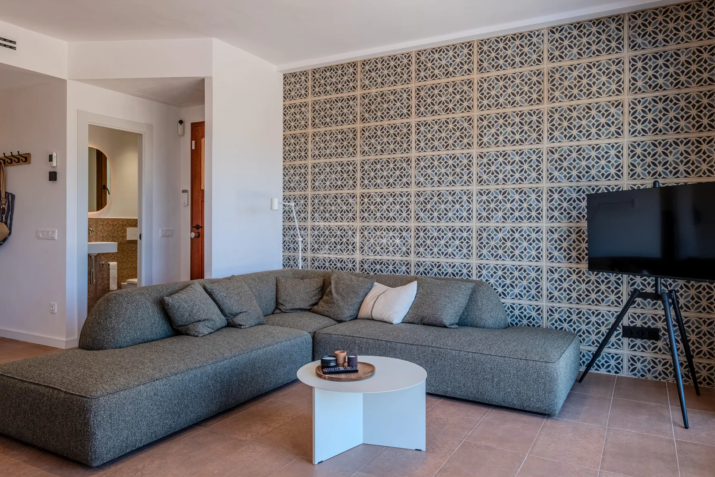 Corner sofa and television against the villa's patterned ceramic feature wall