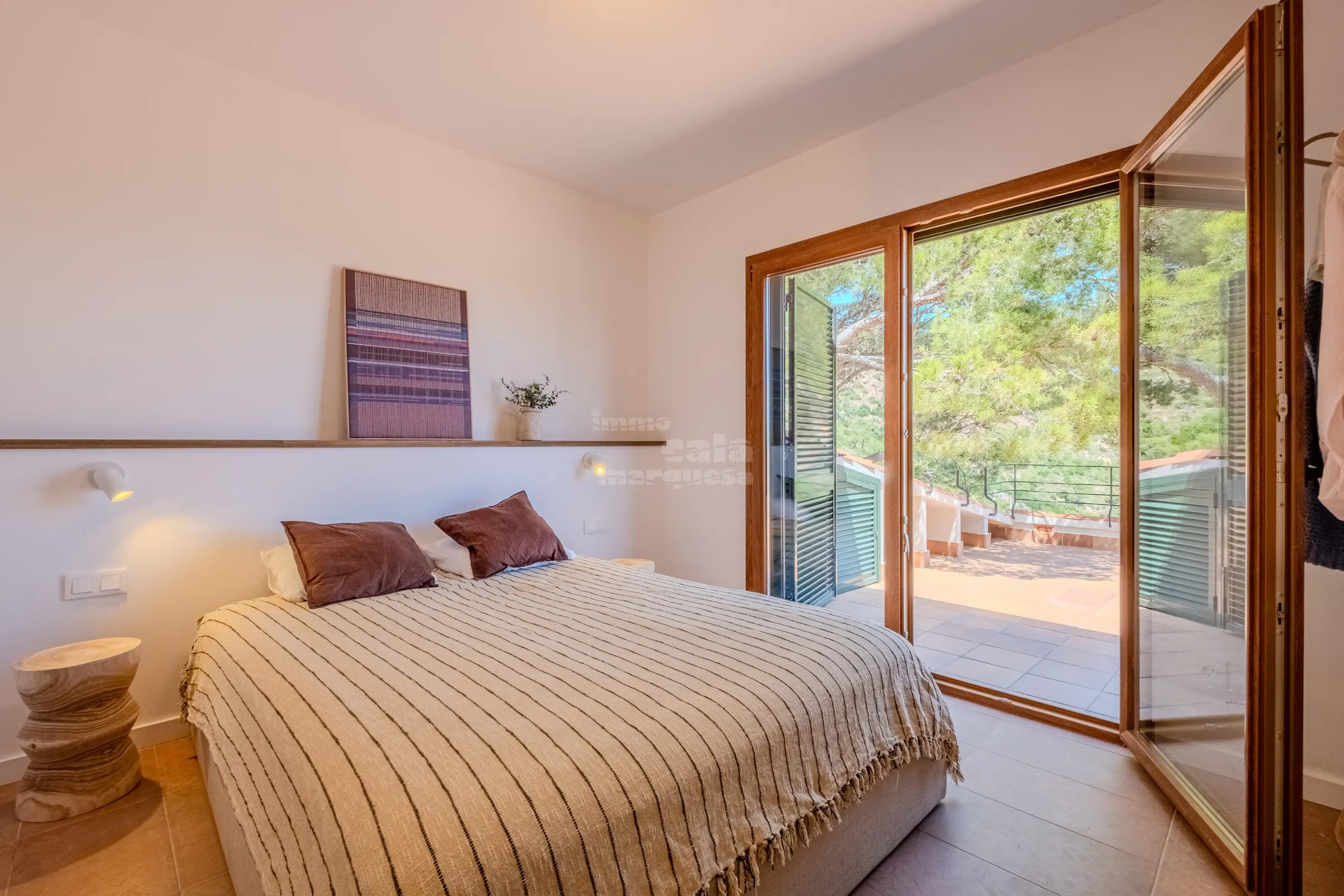 Suite bedroom with double bed opening through glazed doors onto the sea-view terrace