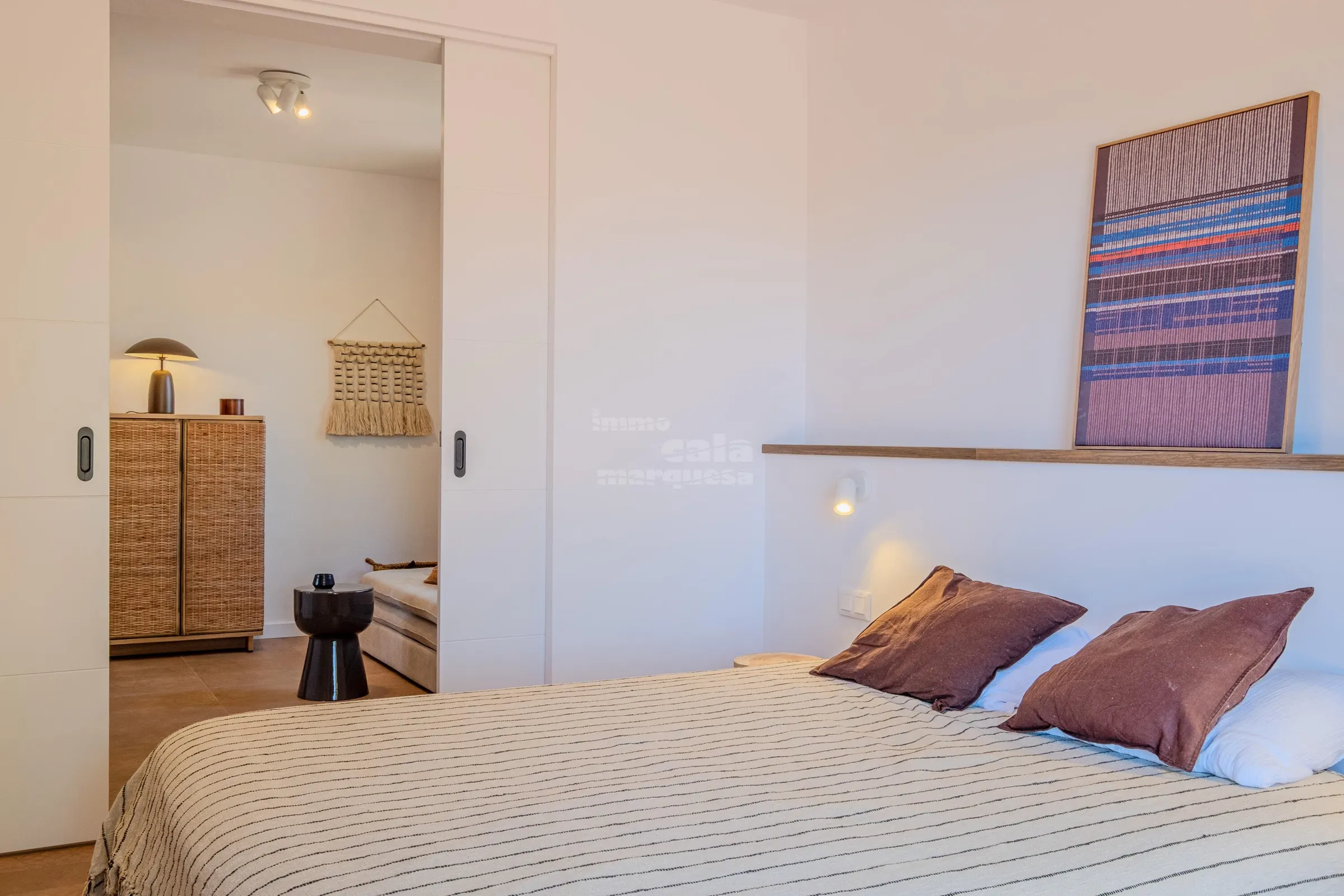 The suite's double bed with terracotta cushions, seen from the lounge doorway